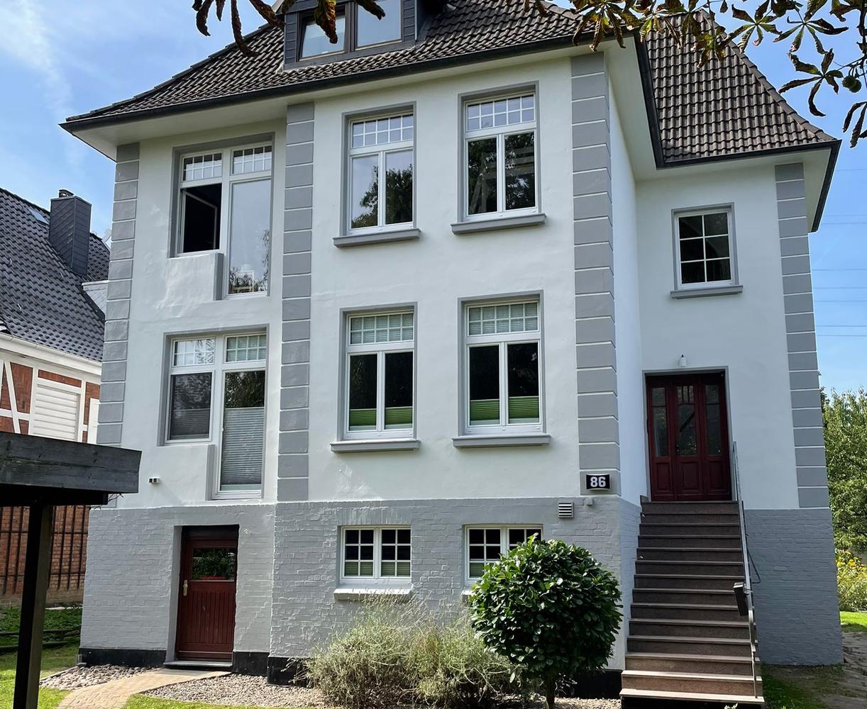 Frisch gestrichene Fassade eines Mehrfamilienhauses mit abgesetzten grauen Faschen